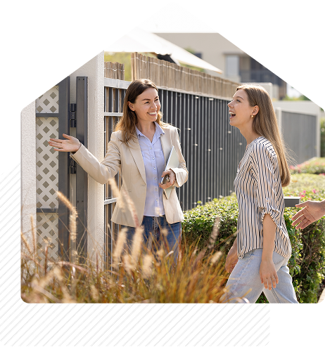 Real estate agent smiling and greeting clients outside a modern home during a property showing.